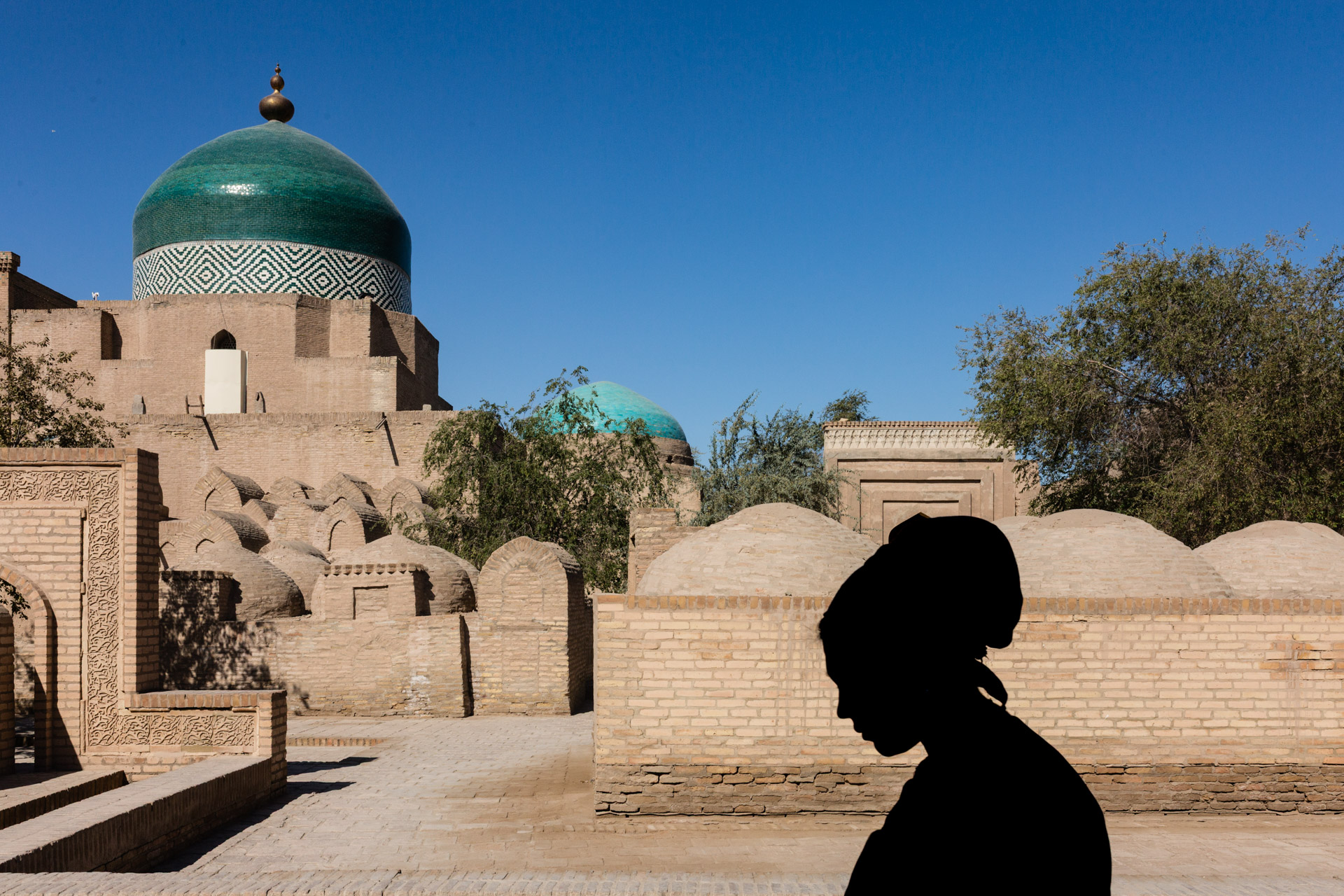 Light and shadow play with the background providing key context, captured in Uzbekistan with a 35mm focal length.